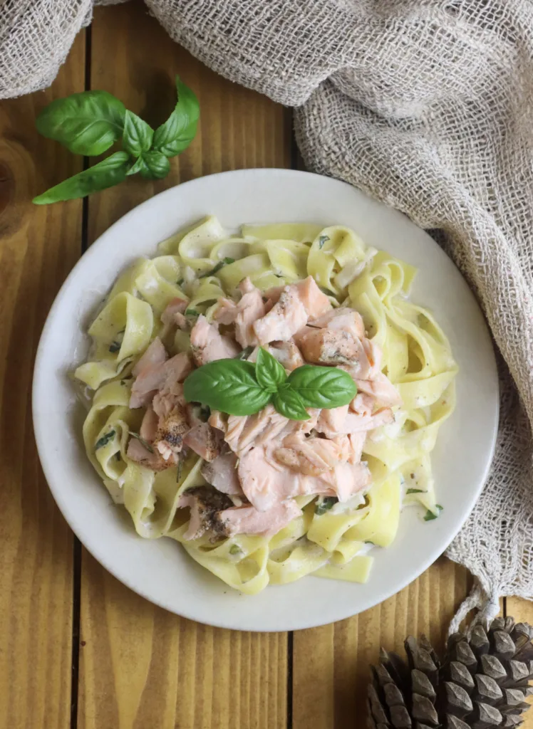 placing pasta and salmone with the sauce to the plate with basil decoration 