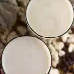 Two glasses of fresh homemade baobab juice with coconut on the table, with baobab fruit pulp in the background.