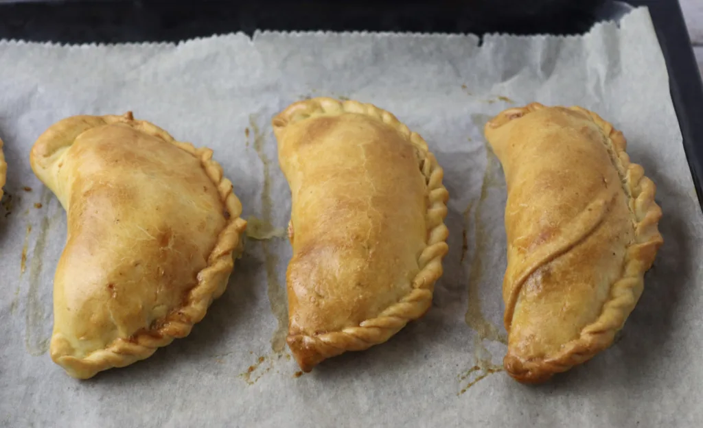 image showing freshly baked empanadas coming out of the oven