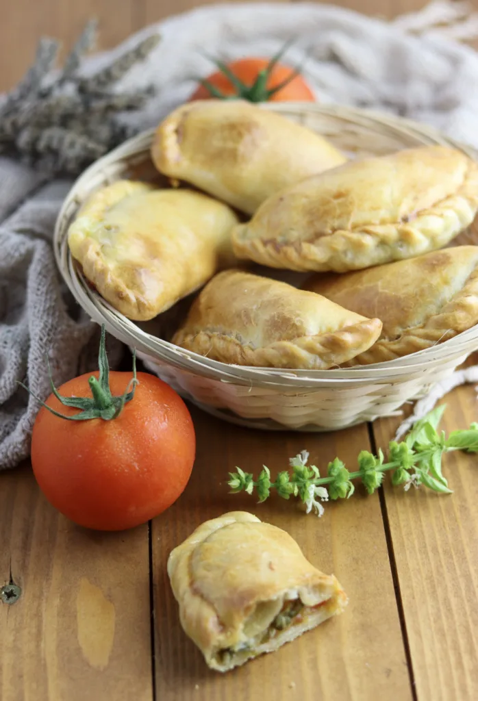 image showing a bite of caprese empanada with a full basket of empanadas in the background