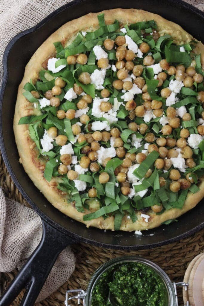 image of wild garlic pizza topped with wild garlic leaves, chickpeas and white feta cheese
