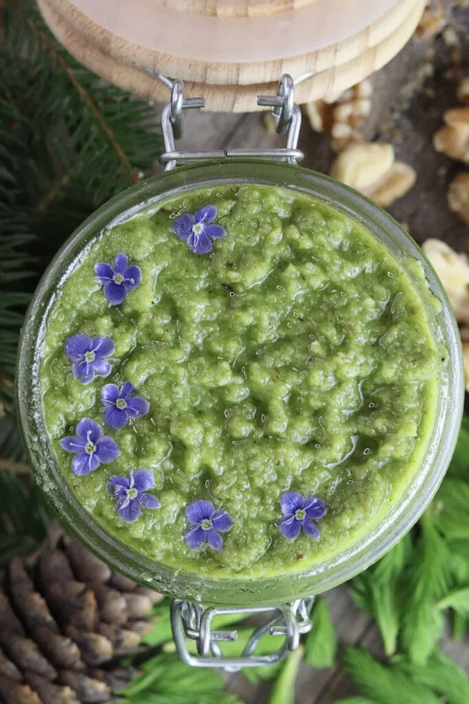 Image of spruce tip pesto in a jar with wild flowers