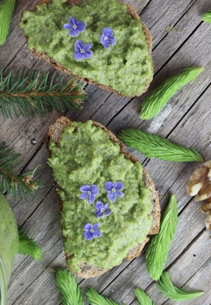 Spruce tip pesto spreaded on bread with flower decoration.