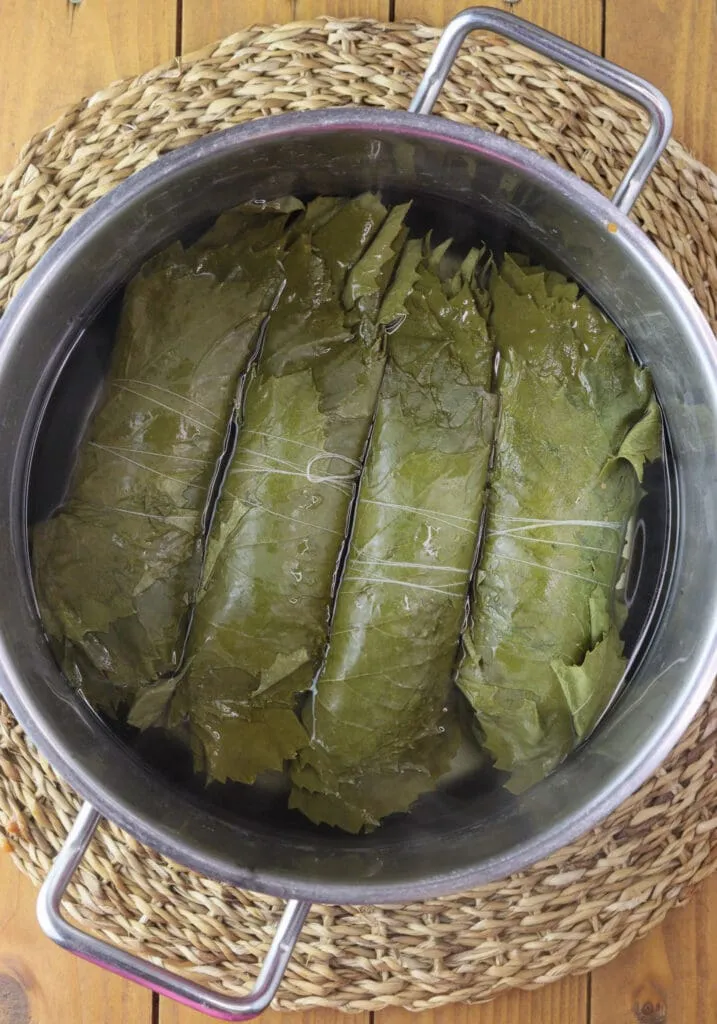 Blanching grape vine rolls for japrak in the winter. 