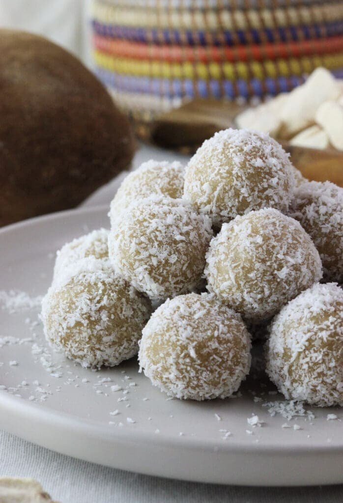 Delicious baobab bites rolled in coconut and stacked on top of eachother with baobab pulp in the background