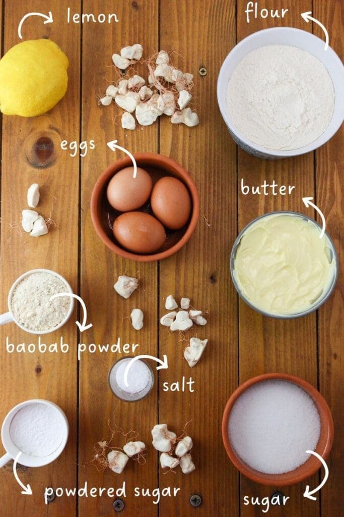 gathering ingredients for lemon baobab cookies: baobab powder, lemon, butter, flour, sugar, eggs and salt