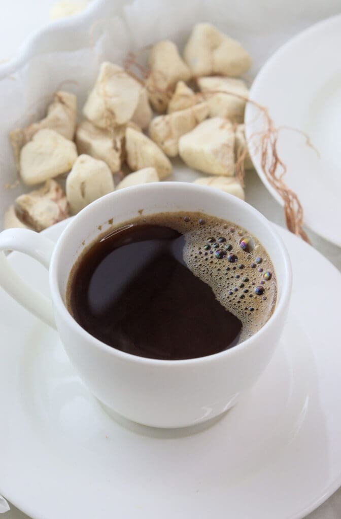 A cup of freshly brewed baobab coffee with baobab fruit in the background.
