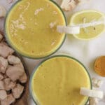 two glasses of healthy baobab smoothie with ginger and baobab fruit in the background