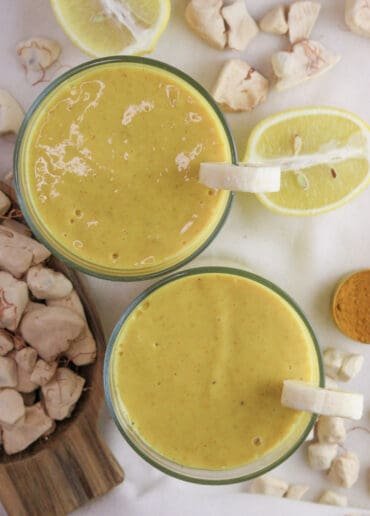 two glasses of healthy baobab smoothie with ginger and baobab fruit in the background