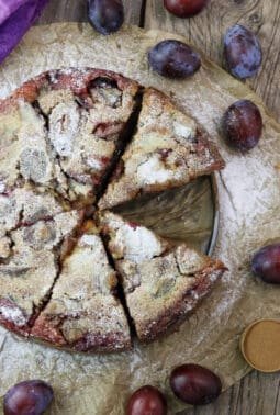 Image of freshly baked buckwheat plum clafoutis with fresh plums in the background