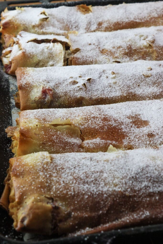 A full baking pan of delicious plum strudel powdered with sugar, the best and the easiest plum dessert.