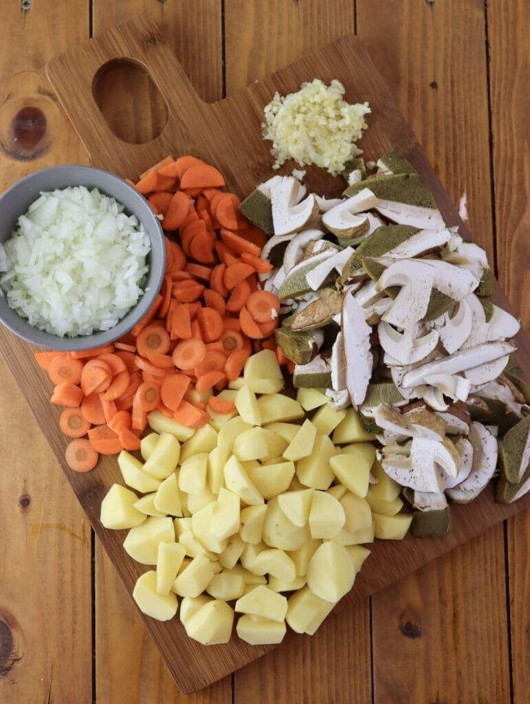 Image of sliced ingredients for porcini soup: onions, garlic, porcini mushrooms, carrots and potatoes