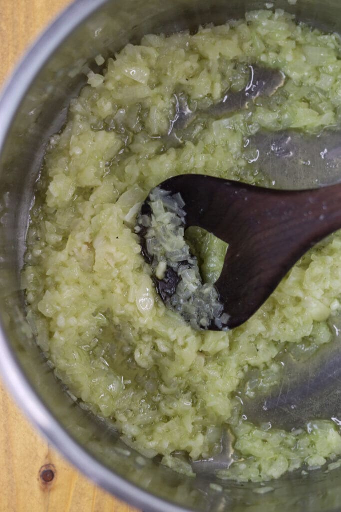 Onions and garlic being fried in olive oil and butter in a large pot.