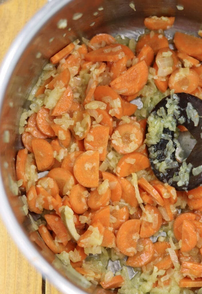 Stir frying the carrots in a large pot before adding potatoes and mushrooms