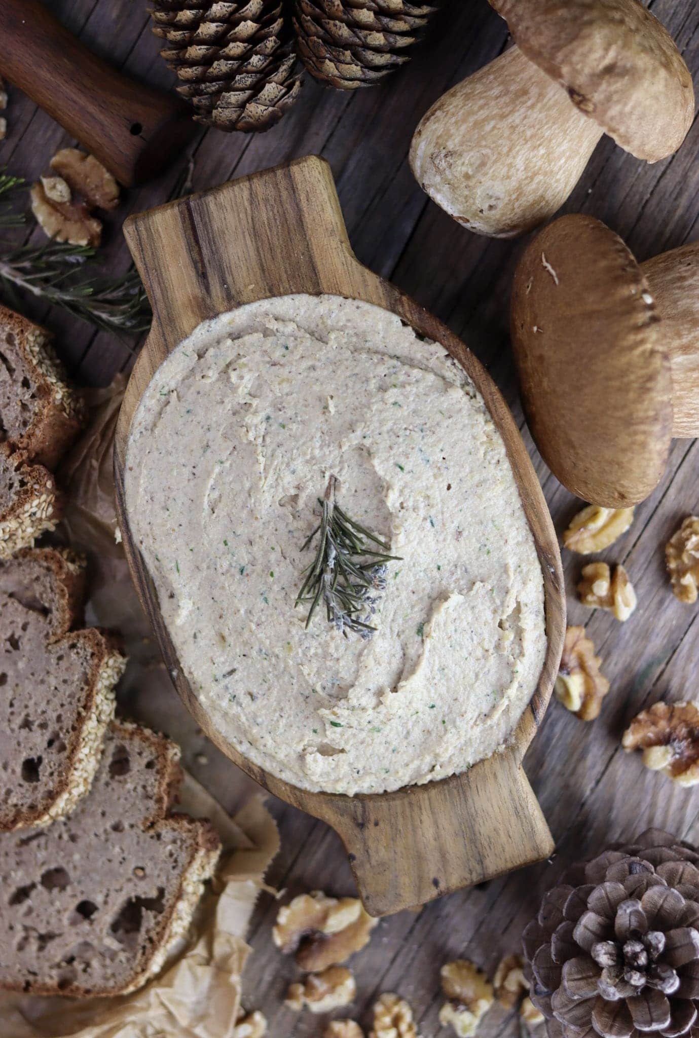 Delicious, creamy porcini mushroom walnut pate with walnuts, porcini mushrooms, rosemary and fresh bread in the background