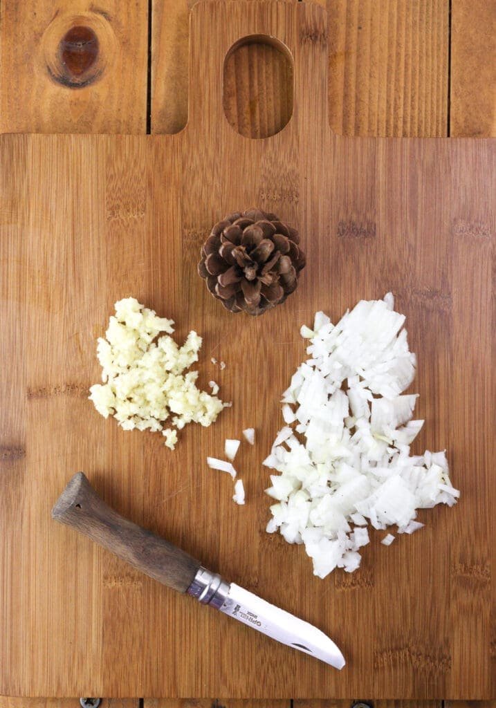 Image showing how to chop the onion and crush the garlic on a cutting board before making the sauce