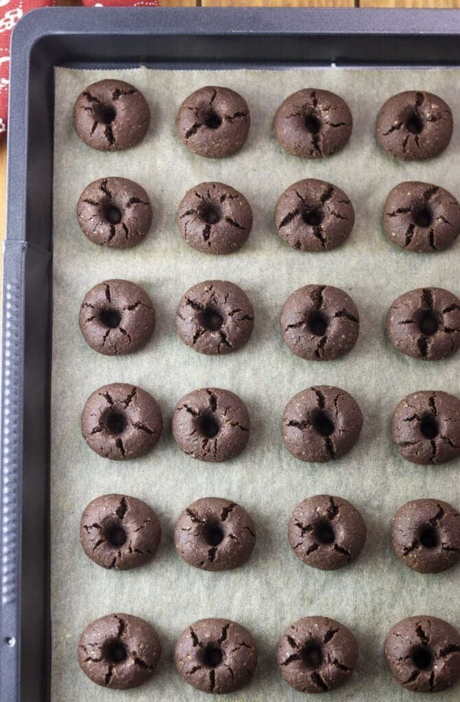 Cookies on a baking tray, just baked, ready to be filled with hot strawberry jam