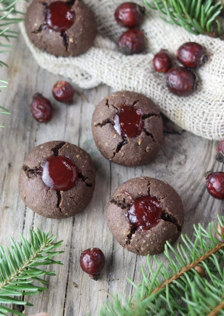 Three buckwheat cookies on a wooden table with silver fir and rosehip buds in the background
