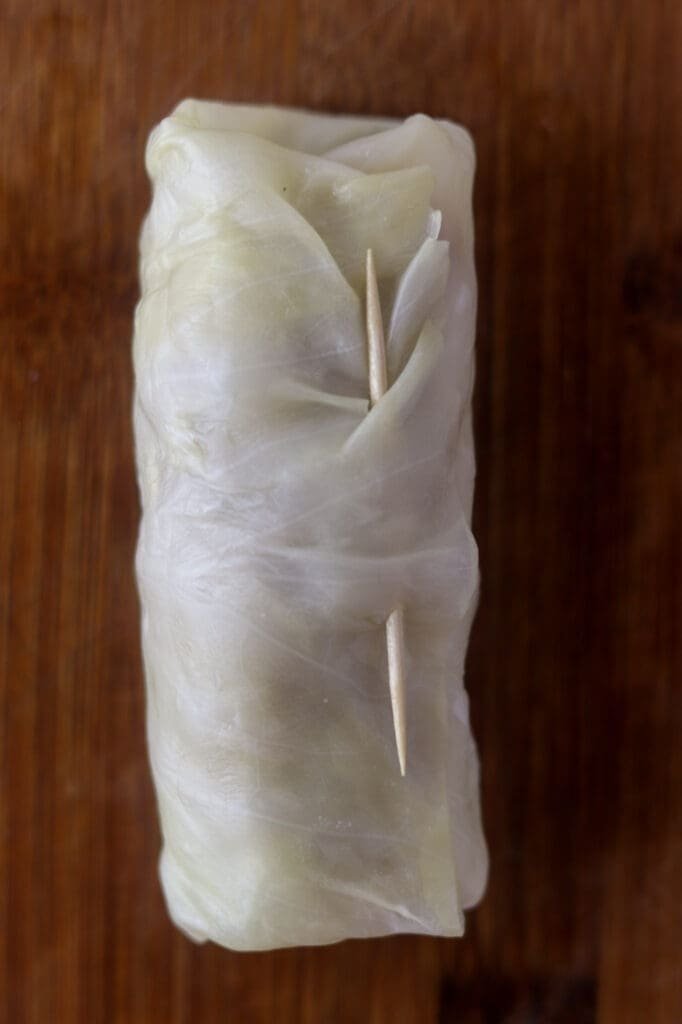 Using a toothpick to close the cabbage roll to ensure it's tightly closed and doesn't fall apart while cooking.