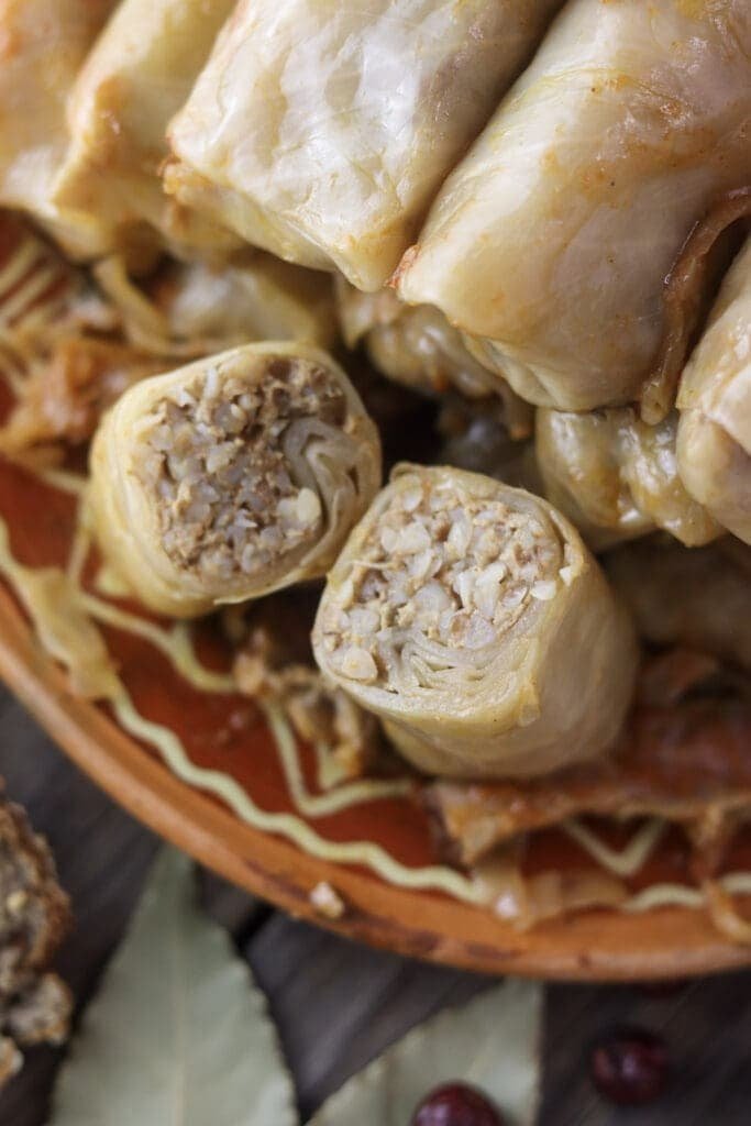 sour cabbage rolls with buckwheat filling, one cut open to reveal the meat and grain stuffing