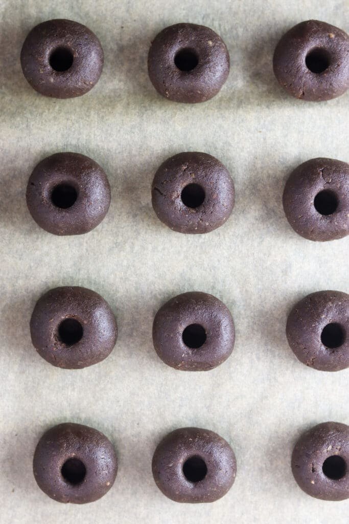 Cookie dough balls assembled, with cavities, ready to be baked.