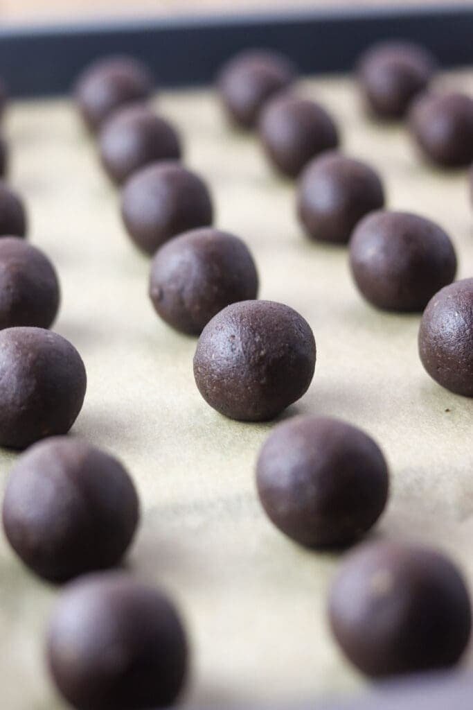 Cookie dough balls placed on a baking tray widely apart.