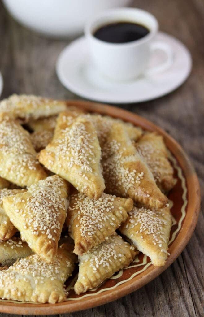 Delicious crackling cookies with sesame seeds served on a rustic table with a cup of coffee.