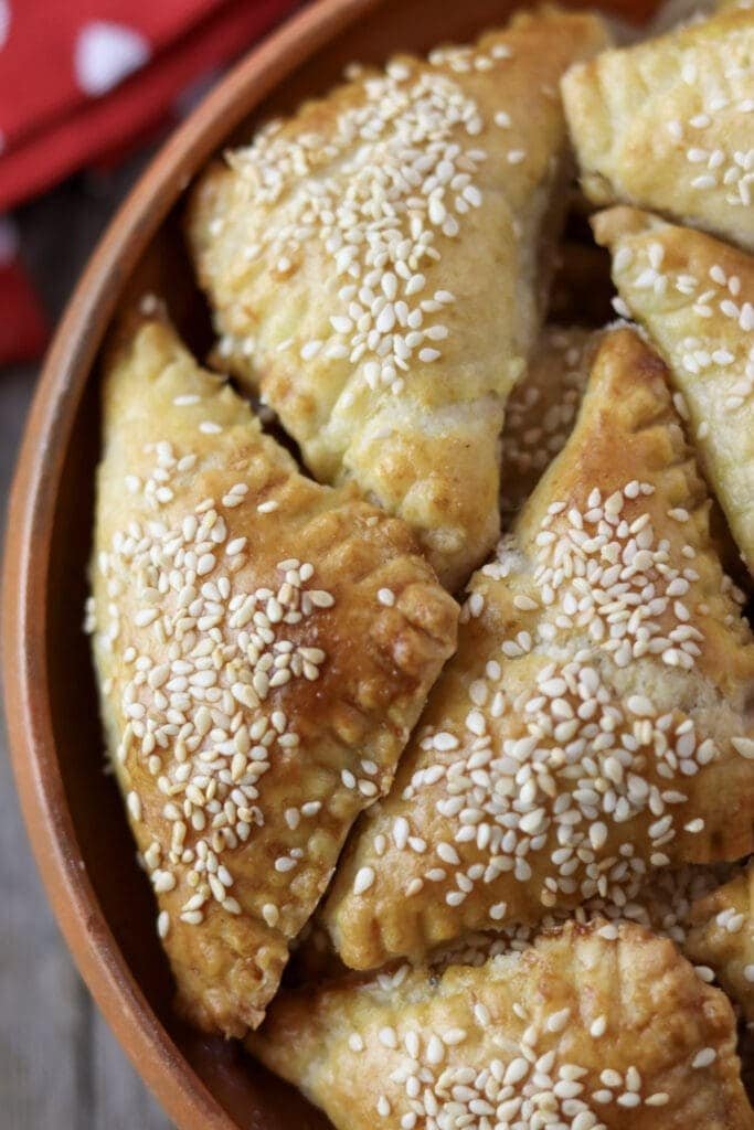 A close view of crispy crackling cookies with sesame seeds in a bowl.