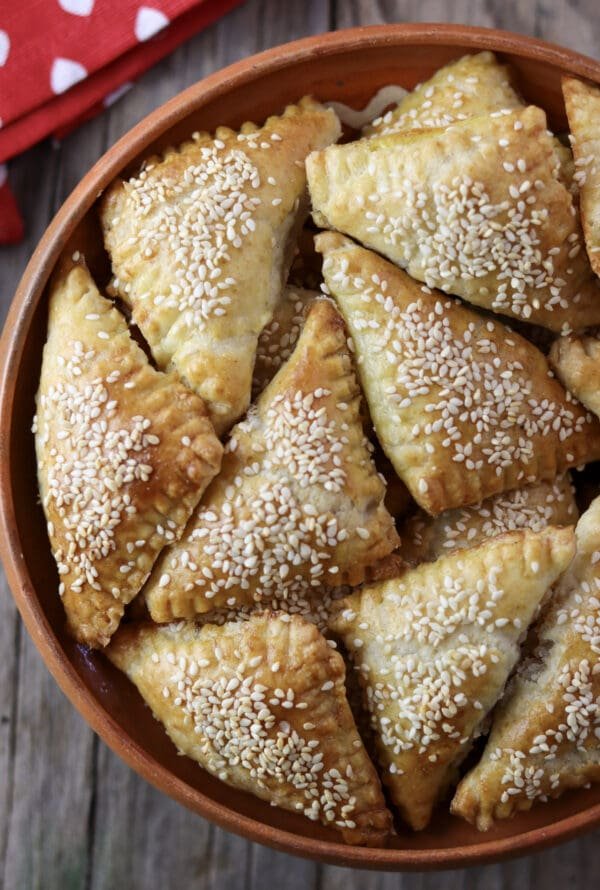 A bowl full of freshly baked crackling cookies with sesame seeds.