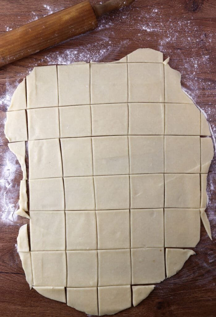 Cutting the dough into squares using a pizza cutter.