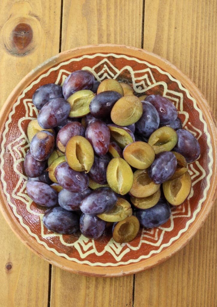 plum halves with removed pits on a clay plate