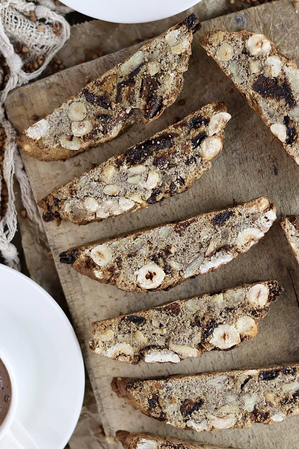Gluten free buckwheat biscotti on a wooden plate with two cups of coffee for a perfect dip