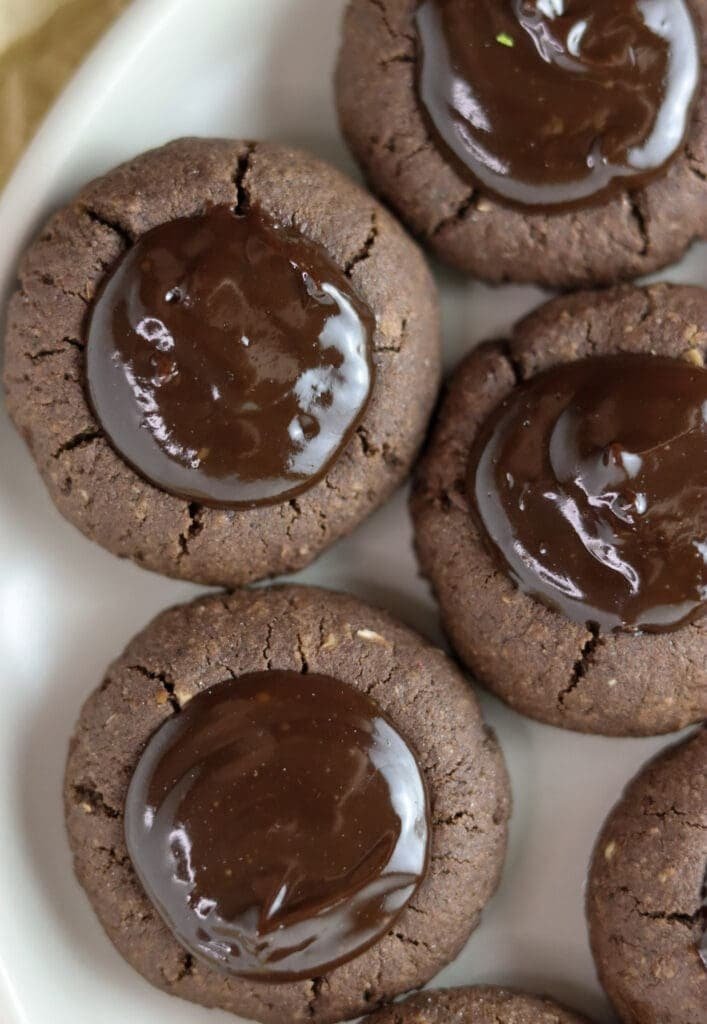 A close shot of three buckwheat thumprint cookies with chocolate.