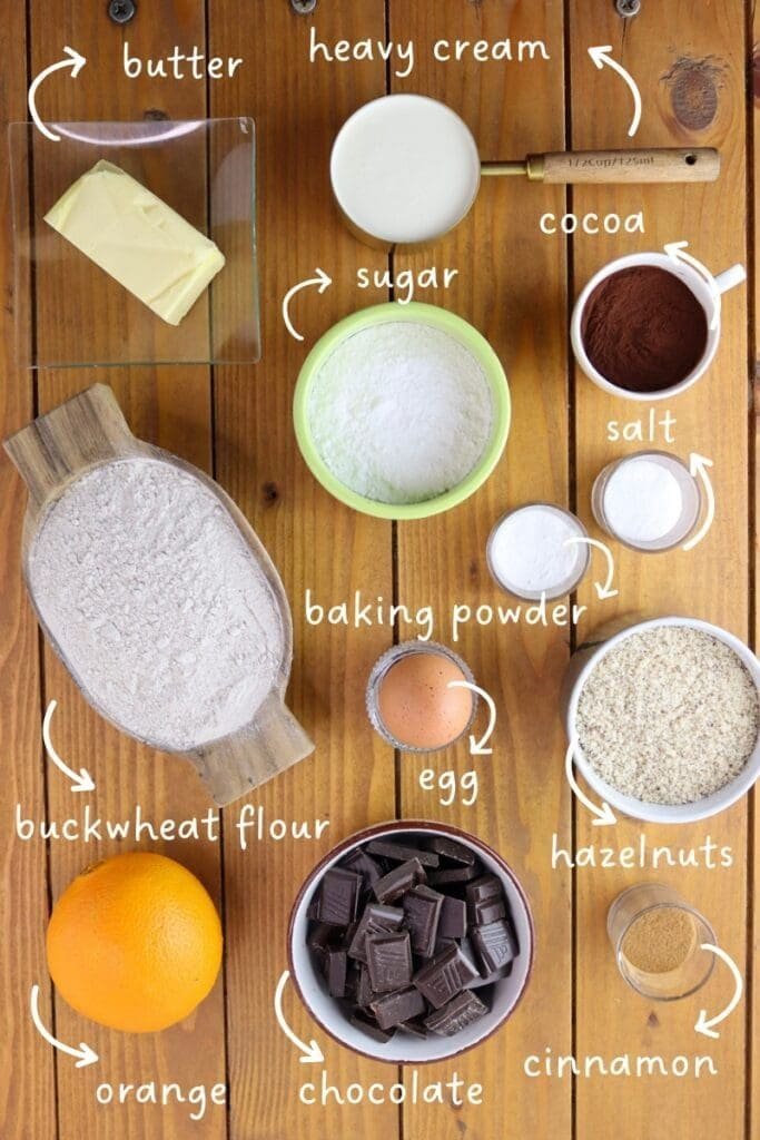Gathering ingredients for buckwheat chocolate thumprint cookies: buckwheat flour, butter, one egg, hazelnuts, powdered sugar, cocoa, baking powder, sea salt, orange zest, heavy cream and chocolate or chocolate chips