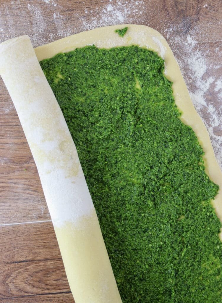 Rolling the dough with wild garlic filling into a large babka log.
