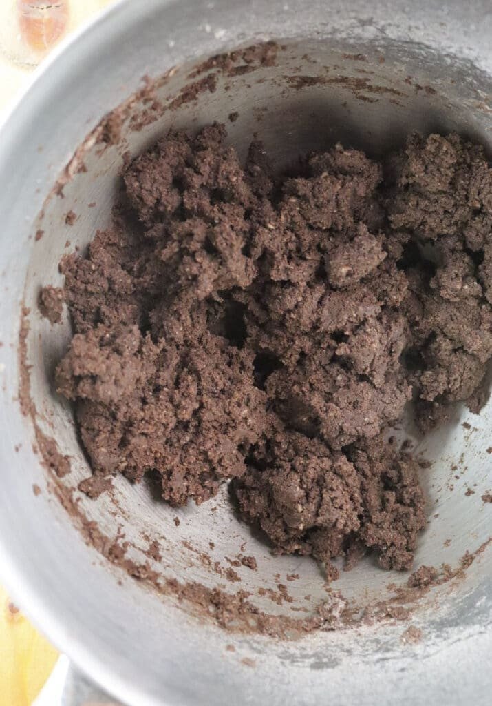 Cookie dough coming together in large crumbs at first, then becoming more buttery and easy to handle.