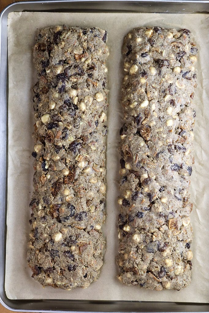Two biscotti dough logs placed on parchment paper lined baking tray, ready for baking.