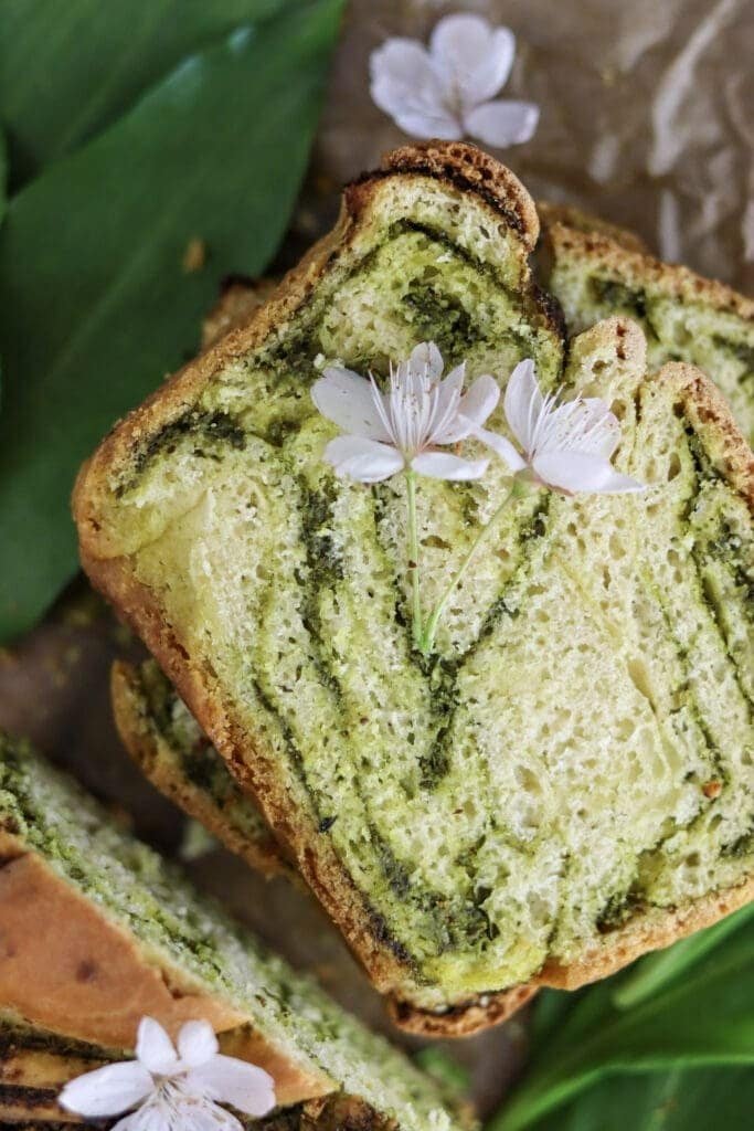 A slice of colorful wild garlic bread with green wild garlic pesto filling.