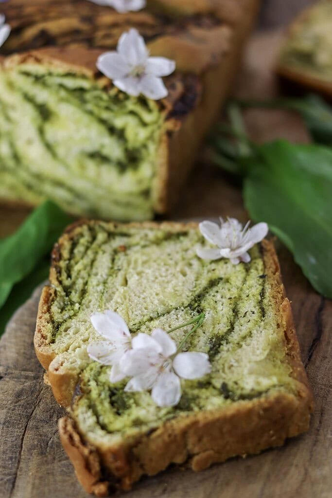 A slice of wild garlice bread on a rustic wooden table, ready to be eaten fresh and warm.