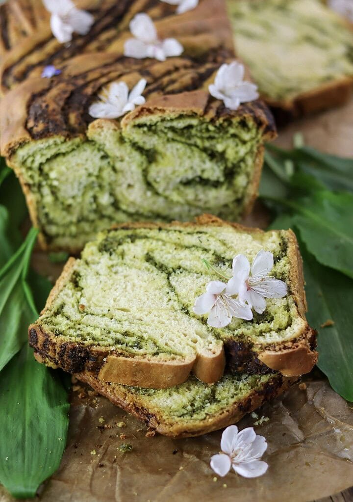 Sliced green wild garlic babka loaf and two pieces of wild garlic bread.